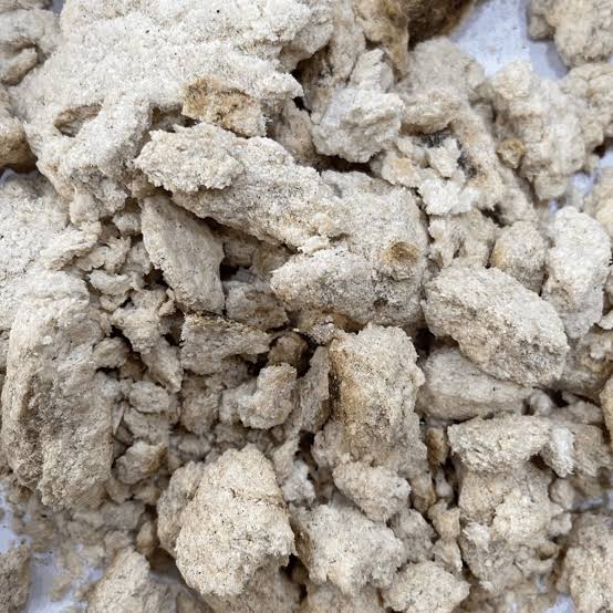 Pressed coconut oil cake pieces prepared for industrial grinding